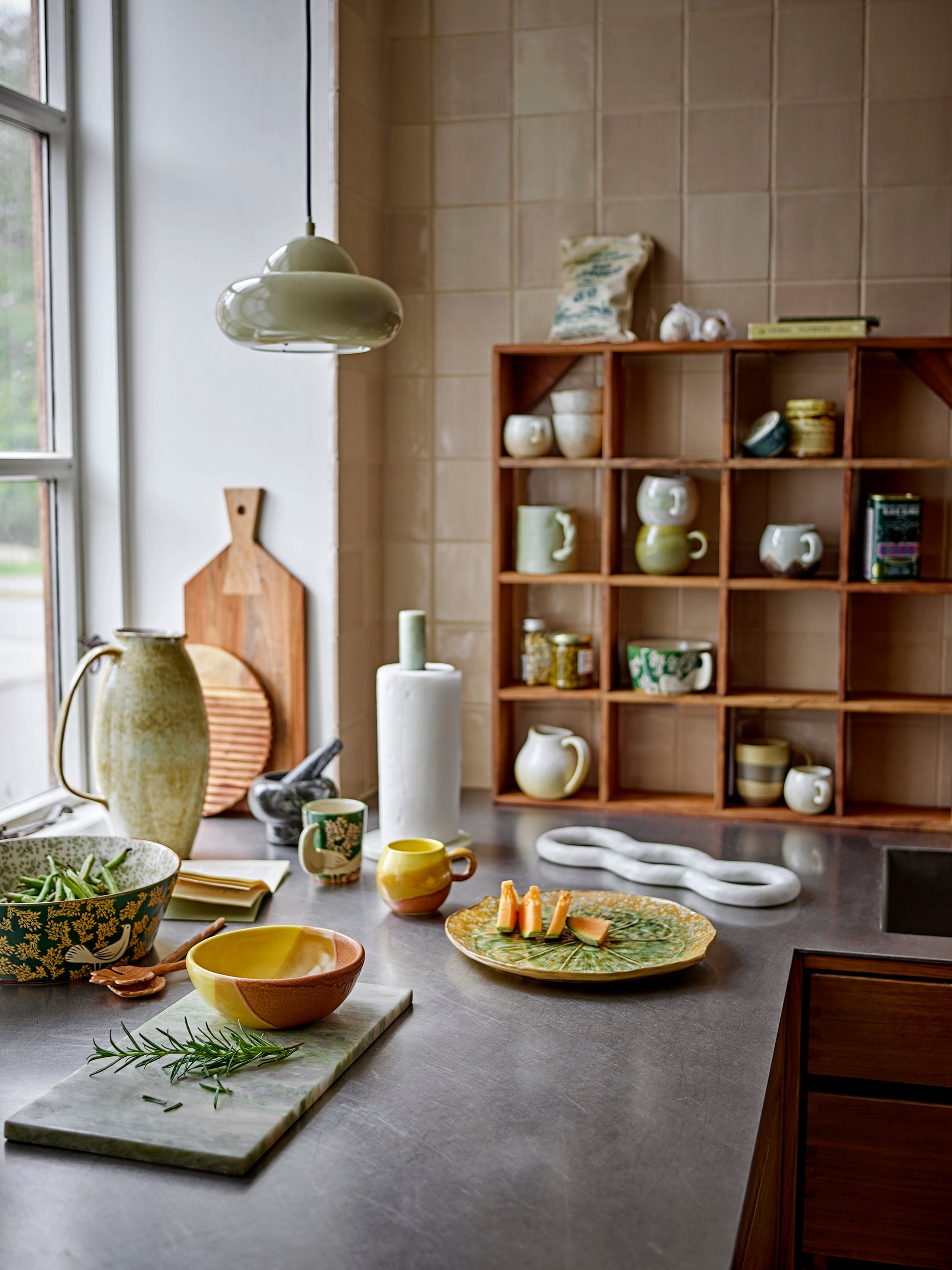Žalia marmuro pjaustymo lenta „Keika“ moderniame virtuvės interjere, derinama su keramikiniais indais.